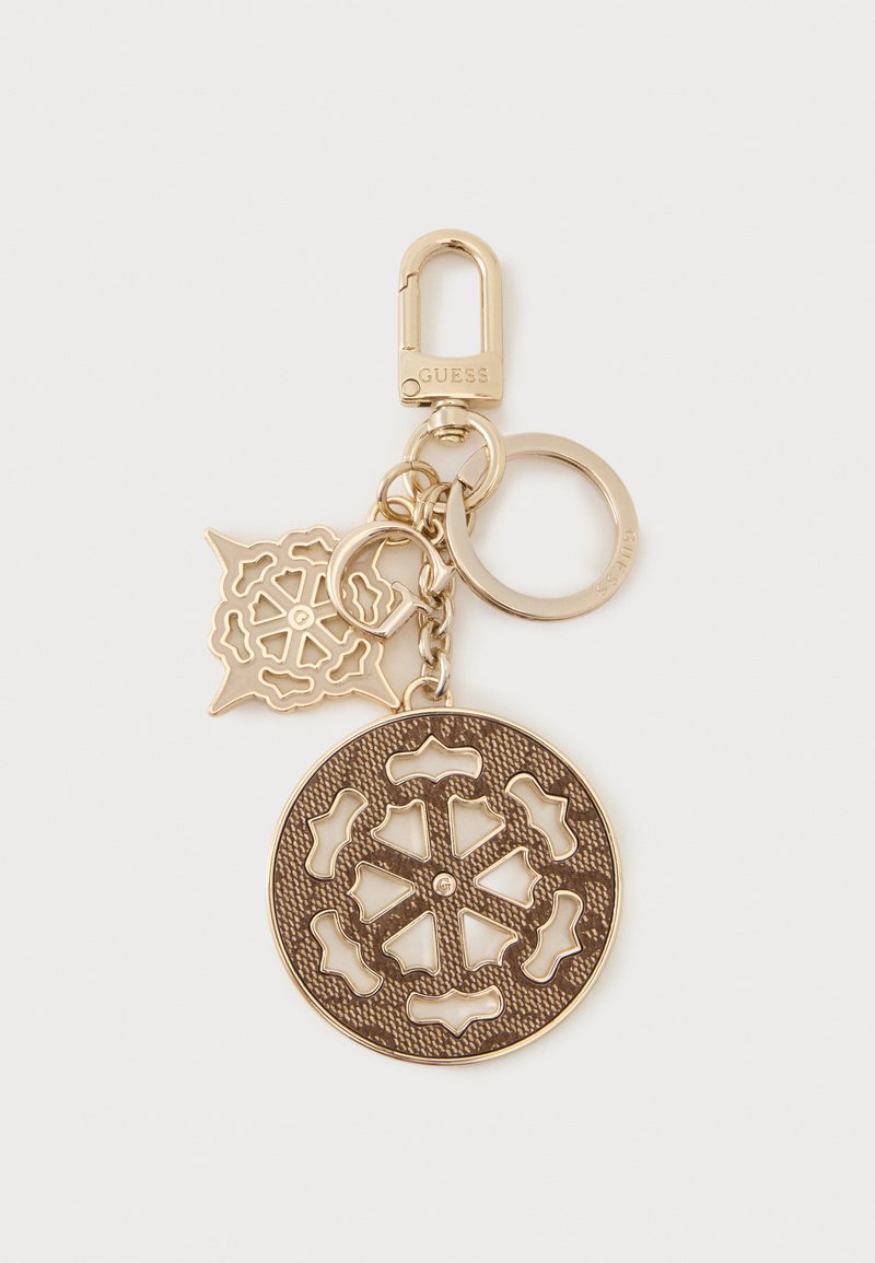 Porte-clés en métal doré avec deux breloques décoratives ajourées et un fermoir gravé du nom de la marque « Guess ».