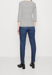 Randig skjorta med trekvartsärm i svart och vitt kombinerad med mörkblå, raka jeans och svarta ankelstövlar med klack.