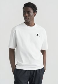 Λευκό βαμβακερό μπλουζάκι με στρογγυλή λαιμόκοψη και κοντά μανίκια, με μικρό μαύρο λογότυπο Jordan στο αριστερό στήθος. Κανονική εφαρμογή και απλός σχεδιασμός.