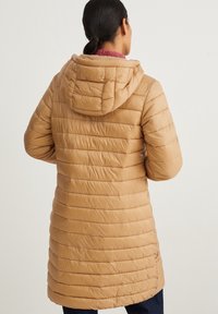 Abrigo largo, acolchado y color topo con capucha, con patrones acolchados horizontales y cintura ajustada. Tela lisa y ligera.