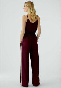 Burgundisches Zweiteiliges Outfit mit einem ärmellosen Top mit V-Ausschnitt und weit geschnittenen Hosen mit weißen Seitstreifen und lässiger Passform.