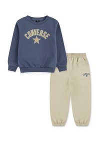 Plava dukserica s natpisom "CONVERSE" i grafikom zvijezde; bež trenirke s elastičnim manžetama i sličnim logotipom. Mekana mješavina pamuka.