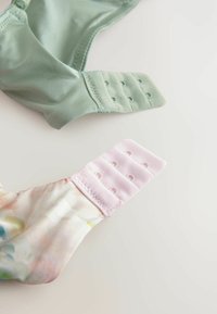 Grøn satin bh-strop med justerbare kroge og en lyserød stofstrop med et blomsterprint og kroge til lukning.