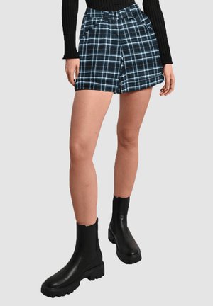 Shorts de cuadro en negro y azul con cintura alta, que cuentan con un cierre frontal y dos bolsillos laterales, combinados con botas negras de tobillo.
