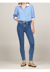 Blå och vitrandig skjorta med korta ärmar, i kombination med figurnära mörkblå jeans och ljusbruna loafers.