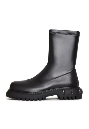 Botte en cuir noire mi-mollet avec une semelle épaisse à crampons et des détails à pointes métalliques au talon, pour un style robuste et une bonne traction.