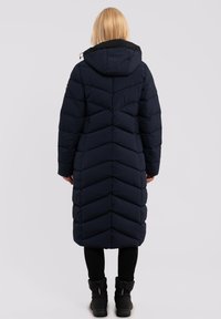 Lungo cappotto in piuma blu navy con un motivo a zig zag, cappuccio regolabile e dettagli neri. Presenta un taglio fino al ginocchio e maniche lunghe.