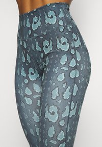 Leggings a vita alta in un motivo maculato blu e nero, realizzati in materiale elasticizzato con una texture liscia e cuciture piatte.