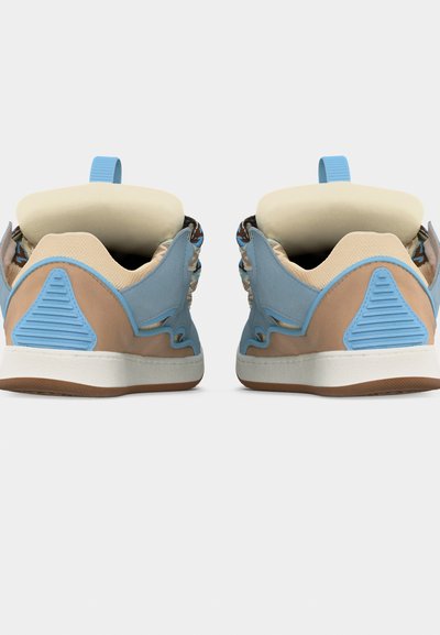 Paire de baskets beige et bleues avec colliers rembourrés et semelles en caoutchouc marron clair, vues de dos sur un fond blanc.