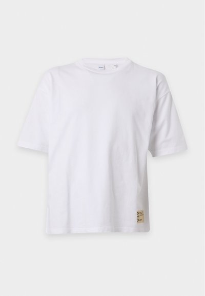 T-shirt blanc à manches courtes et col rond avec une petite étiquette rectangulaire beige près de l'ourlet inférieur côté droit.