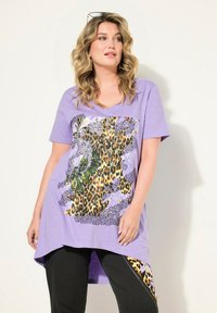 Fialové tričko s krátkými rukávy a V v�ýstřihem, které se vyznačuje velkým květinovým a leopardím vzorem. Měkká látka s delší zadní částí pro zvýšenou ochranu.