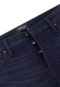 Jeans de mezclilla de un azul oscuro con una vista en primer plano de la cinturilla y el cierre de botones. Presenta una etiqueta negra con la marca "JACK & JONES".