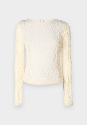 Lange mouwen crème top met een gestructureerd patroon, ronde halslijn en subtiele rimpels langs de randen. Lichtgewicht, delicate stof.