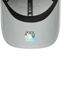 Gorra gris con un diseño estructurado, acentos negros y visera plana. Presenta una etiqueta del logo de la NFL en la parte inferior.