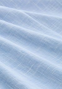 Hellblauer Stoff mit einem kleinen karierten Muster, der eine glatte Textur und sanft fließende Vorhänge aufweist. Ein subtiler Glanz reflektiert das Licht.