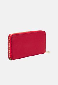 Portofel roșu din piele cu o finisare texturată, închidere cu fermoar și accente din metal de aur. Formă rectangulară, cu margini netede și un design compact.