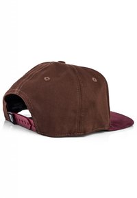 Smeđa tkanina kapa s tamnijim smeškim vizirima. Na leđima se nalazi maroon podesivi pojas. Zapaženi šavovi na telu.