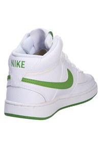 Zapatillas altas blancas con acentos verdes, que cuentan con un exterior de cuero texturizado, un collar acolchado y un destacado logo de Nike en el talón.