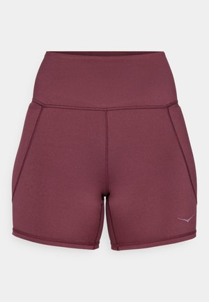 Burgunderfargede treningsshorts laget av elastisk stoff, med høy midje, sidepaneler, og en liten logo på den nedre siden.