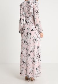 Abito maxi fiorato rosa con maniche a volant, motivi floreali in bianco e nero e vita aderente. Tessuto morbido con una silhouette fluida.