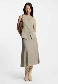 Beżowa, dopasowana sukienka bez rękawów z przodem na guziki i rozkloszowanym dołem. Gładka faktura; zestawiona z beżowymi kozakami za kolano i torebką w kolorze brązowym.