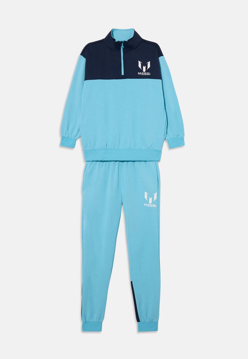 Dres w jasnoniebieskim kolorze z granatowymi akcentami. Rozpinana bluza z wysokim kołnierzem, elastycznymi mankietami oraz dopasowane spodnie z białymi detalami logo.