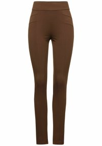 Bruna leggings med hög midja, tillverkade av elastiskt material. Har böjda sömmar fram och en jämn yta. Skräddarsydd passform.