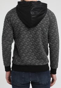 Felpa con cappuccio a motivo esagonale nero e grigio, con cappuccio nero liscio, polsini e orlo a costine. Corpo strutturato con un design moderno.