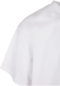 T-shirt en coton blanc à manches courtes, avec un col rond et une texture lisse. Vue arrière montrant l'épaule et un léger drapé du tissu.