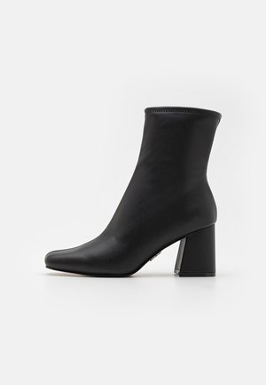 Schwarze Ankle-Boots aus glattem Leder mit spitz zulaufender Zehenpartie und dicker, rechteckiger Absatz. Verfügt über eine gestickte obere Kante für zusätzlichen Detailreichtum.
