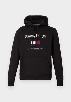 Schwarzer Tommy Hilfiger Hoodie mit vorderer Kängurutasche, Kordelzugkapuze, Markennamen, Flaggenlogo und dem Schriftzug „Established MCMLXXXV New York City“.