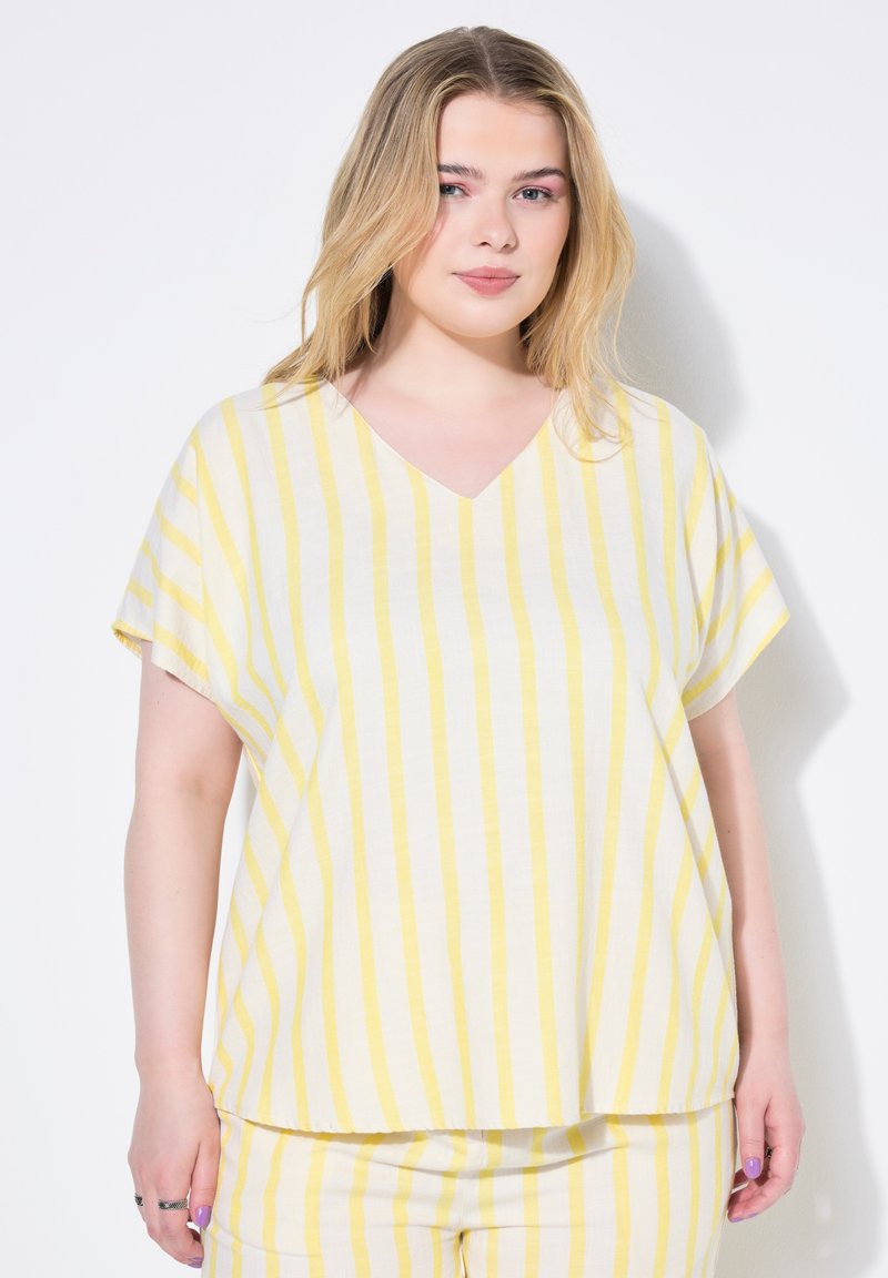 Top à col en V, à manches courtes, en tissu léger. Présente des rayures horizontales blanches et jaunes. Coupe ample avec un ourlet droit.