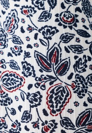 Witte stof met marineblauwe en donkerrode bloem- en bladpatronen in een herhalend ontwerp.