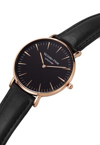 Reloj redondo negro con una caja en tono dorado, correa de cuero negro y marcadores de horas blancos. Presenta el nombre de la marca "Victoria Hyde" en la esfera.