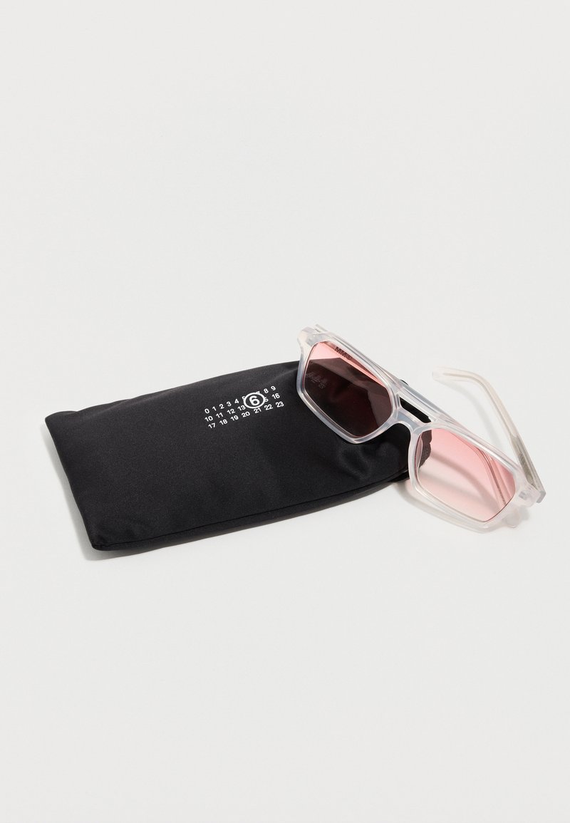 Lunettes de soleil rectangulaires transparentes avec des verres roses reposant sur une pochette en tissu noir ornée d'un motif numérique blanc.