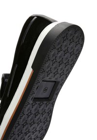 Black suede sneaker with a rubber sole featuring a geometric pattern, white midsole, and an orange accent stripe along the edge.