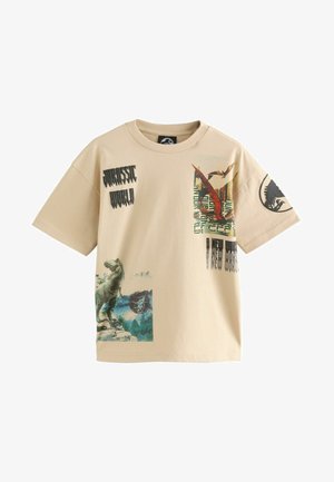 T-shirt in cotone beige con grafiche di dinosauri, testo "Jurassic World" e un logo rotondo. Maniche corte e vestibilità standard.
