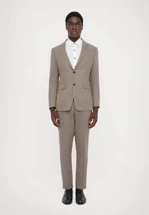 Grau meliertes Anzug mit taillierter Passform, einreihigem Blazer und Reverskragen. Weißes Hemd mit schwarzen Knöpfen darunter. Schwarze Schuhe.