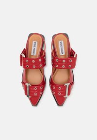 Raudoni blizgūs patentiniai slingback tipo bateliai su smailiais pirštais, turintys dvi plačias juostas su metalinėmis detalėmis ir skylutėmis. Etiketės matomos viduje.