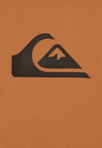 Camiseta de algodón naranja con un gran logo negro de un diseño de montaña y ola centrado en la tela, con una superficie texturada.