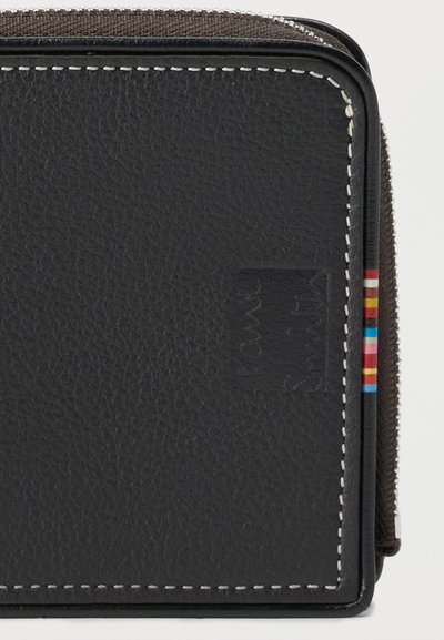 Μαύρο πορτοφόλι από δέρμα με υφή, λευκές ραφές, ανάγλυφο λογότυπο και πολύχρωμη υφασμάτινη ετικέτα με ρίγες στη δεξιά πλευρά.