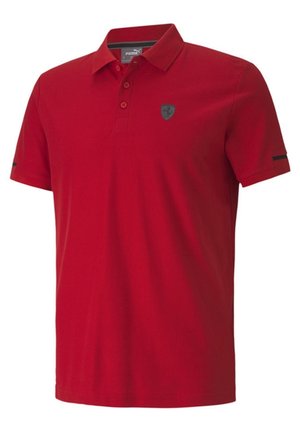 Rotes Polohemd mit kurzen Ärmeln, Kragen und drei Knöpfen, mit einem kleinen dunklen Emblem auf der linken Brust und einem schmalen schwarzen Streifen an den Ärmeln.
