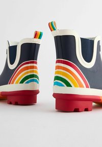 Stivali di gomma navy per la pioggia con strisce multicolori a forma di arcobaleno sul tallone, dettagli bianchi e suola rossa. Due maniglie di rilievo nei colori dell'arcobaleno.