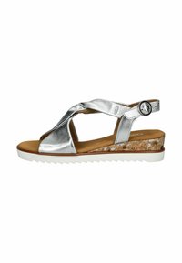 Sandalias metálicas plateadas con diseño de tiras cruzadas, tacón de cuña de corcho y suela blanca dentada. Hebilla ajustable en la correa del tobillo.