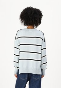 Hellblau gestreifter Pullover mit schwarz-weißen horizontalen Streifen, geripptem Saum und lockerer Passform, kombiniert mit dunklen Jeans.