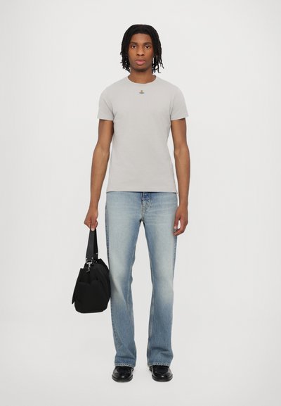 Tricou gri cu mânecă scurtă, cu un mic model brodat, asortat cu blugi din denim de culoare albastră deschisă și o geantă de umăr neagră.