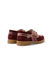 Paire de chaussures bateau en daim bordeaux et rose avec semelles en caoutchouc marron, lacets latéraux et coutures visibles sur fond blanc.