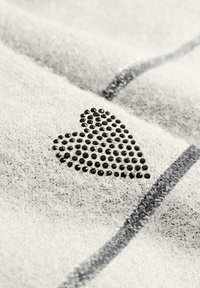 Grijze textiel met een fuzzy textuur, voorzien van een zwart rhinestone hartontwerp en dunne strepen in een donkerder grijs. V