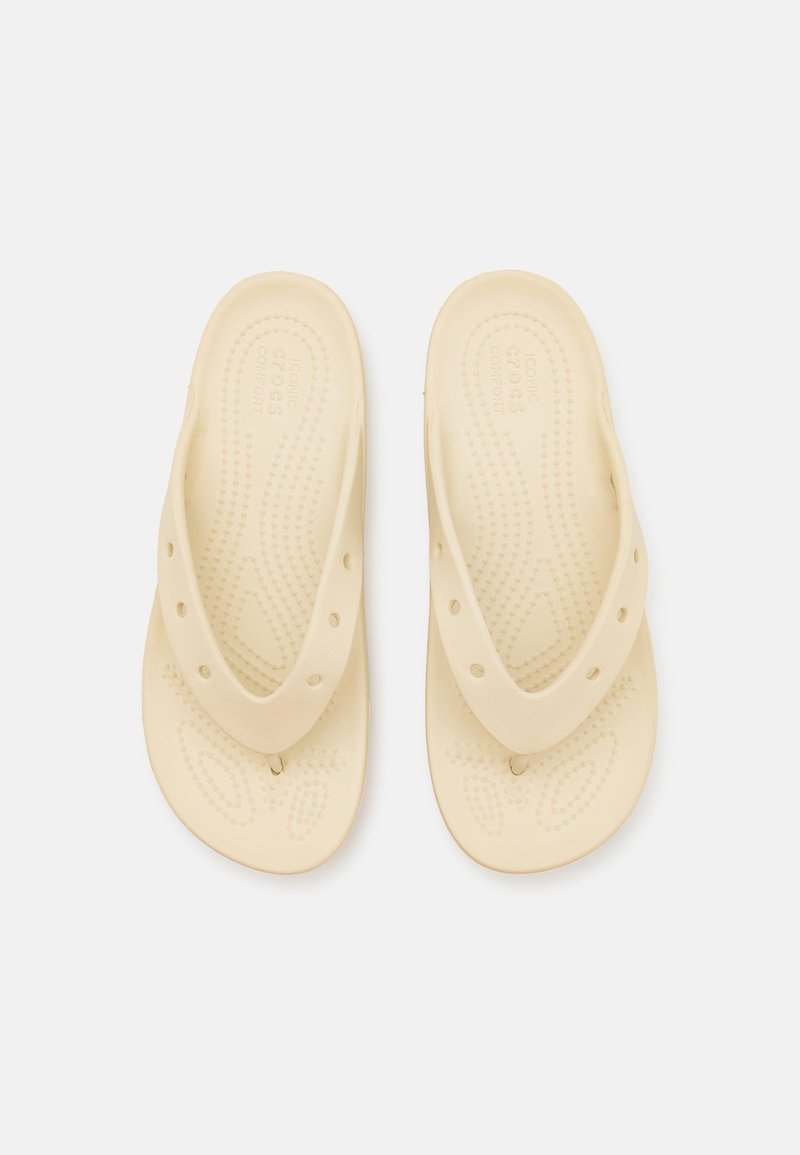Beige Flip-Flops aus weichem Material mit einer strukturierten Fußbett, ausgestattet mit einem Zweiriemen-Design und Belüftungsöffnungen für Atmungsaktivität.