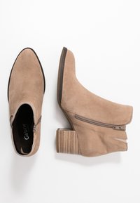 Kostki z zamszu w kolorze taupe z lekko spiczastym noskiem, bocznym zamkiem błyskawicznym oraz słupkowym, żebrowanym obcasem. Miękka tekstura z eleganckim designem.